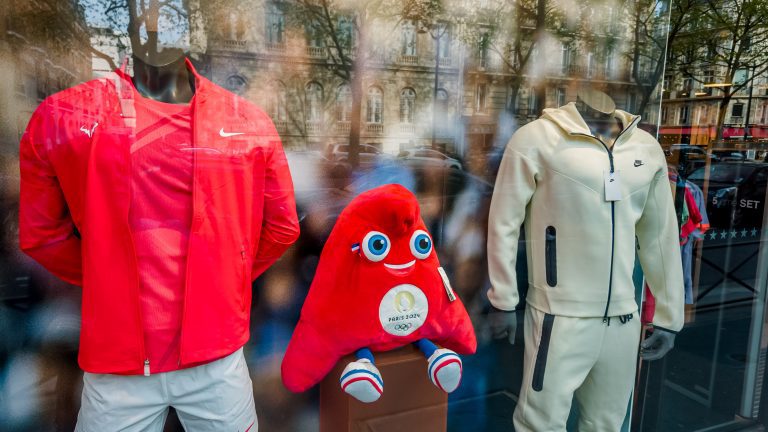 Colorful window display in Paris, France, on April 14th, 2024, featuring a Paris 2024 Olympic mascot plush with sportswear, celebrating upcoming international sports events