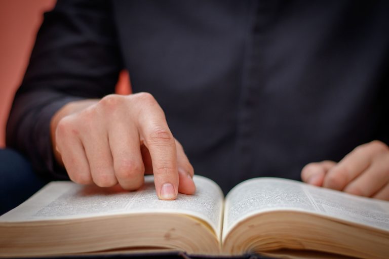 Hands folded in prayer on a Holy Bible in church concept for fai